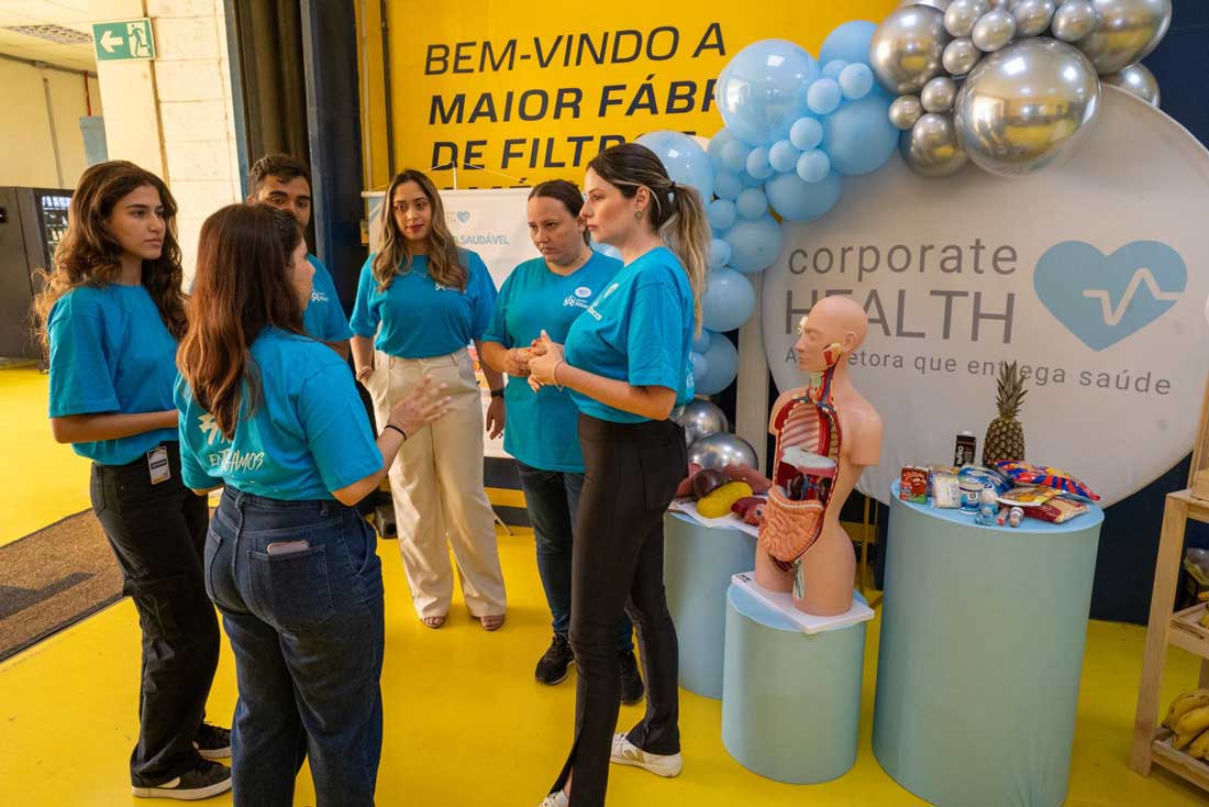 Colaboradores do Grupo Ritacco uniformizados e reunidos de pé em evento expositor.